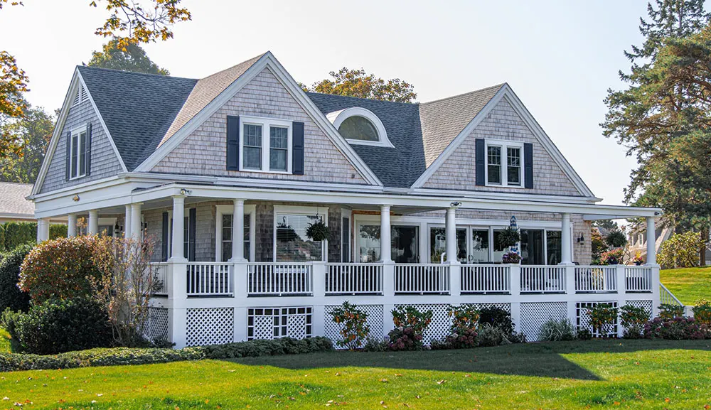 White house with a wraparound porch and landscaped lawn
